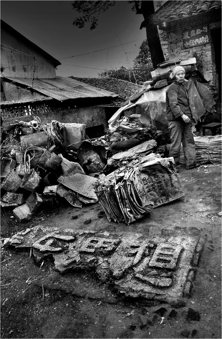 #007-003 This is a recycle collection yard. The broken slab in the foreground says "Mao Zedong Thought," the all-encompassing ideology of the PRC that became an extreme orthodoxy during the terrible years of the Cultural Revolution (1966-76). This broken slogan would have brought a death penalty in that era to the persons responsible.